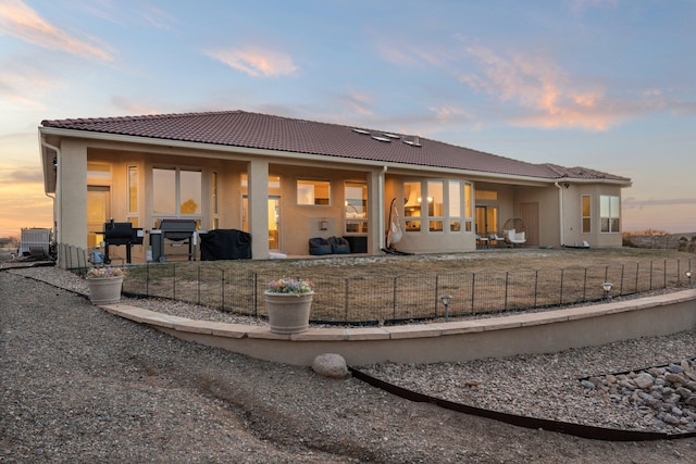 back house at dusk featuring central AC unit and a patio area