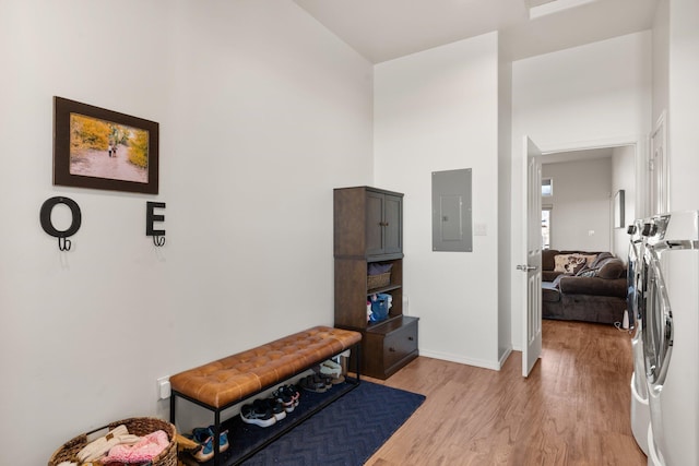 hall featuring washing machine and dryer, electric panel, and light hardwood / wood-style flooring