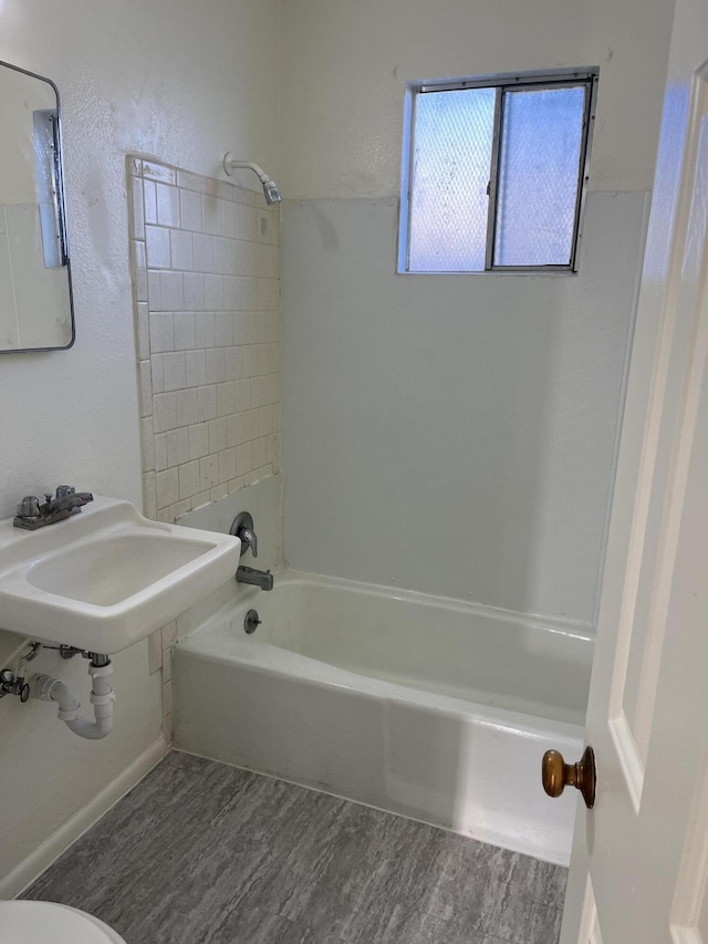 full bathroom with hardwood / wood-style flooring, toilet, tiled shower / bath combo, and sink