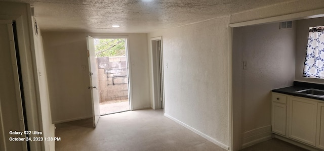 corridor with sink and a textured ceiling