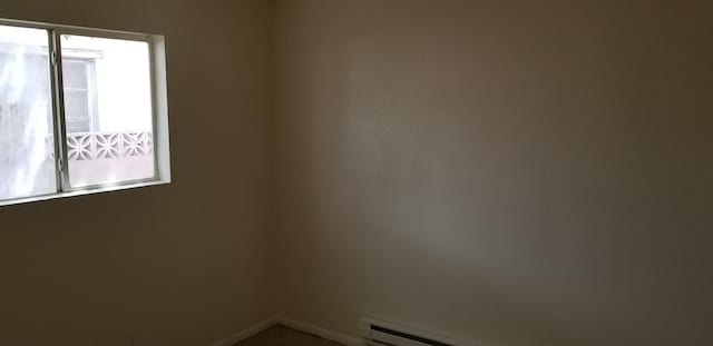 spare room featuring a baseboard heating unit and a healthy amount of sunlight