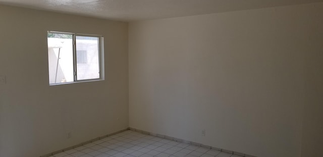 spare room with light tile patterned floors and a textured ceiling