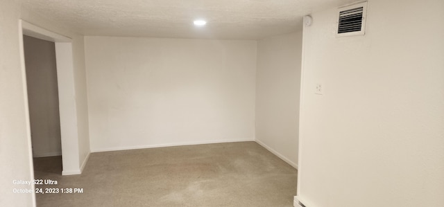 carpeted empty room featuring a textured ceiling