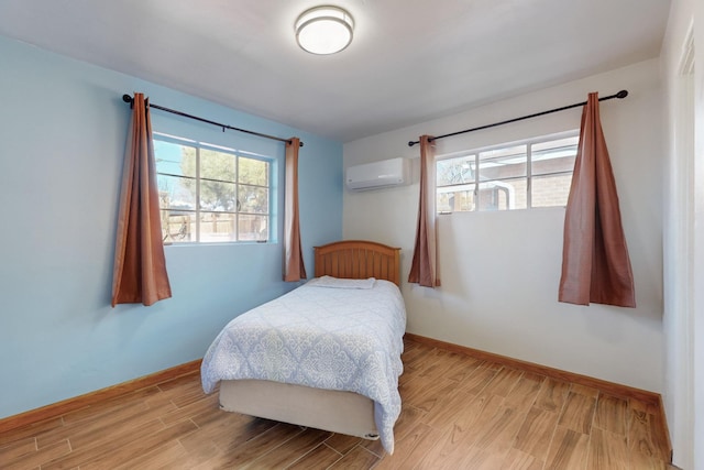 bedroom featuring a wall mounted AC and light hardwood / wood-style flooring