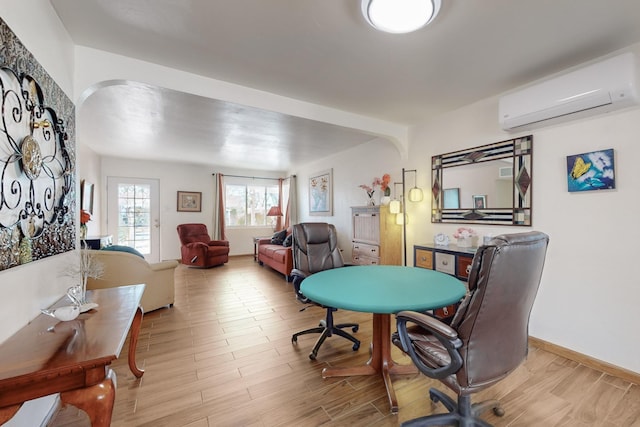 office with a wall mounted AC and light wood-type flooring