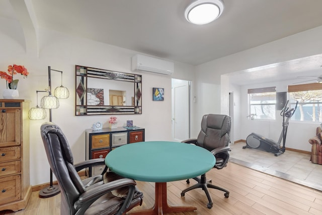 office space featuring an AC wall unit, ceiling fan, and light hardwood / wood-style flooring