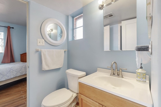 bathroom featuring hardwood / wood-style flooring, vanity, plenty of natural light, and toilet