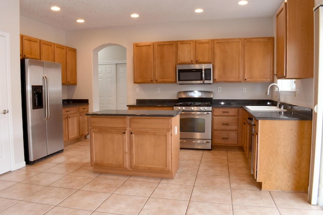 kitchen with sink, stainless steel appliances, a center island, and light tile patterned flooring