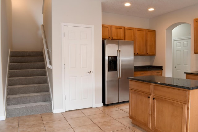 kitchen with light tile patterned flooring, a kitchen island, and stainless steel fridge