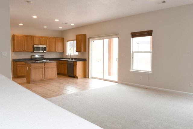 kitchen featuring a kitchen island, appliances with stainless steel finishes, sink, and light carpet