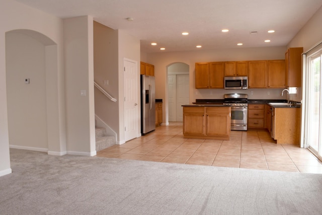 kitchen featuring light tile patterned flooring, appliances with stainless steel finishes, sink, and a kitchen island