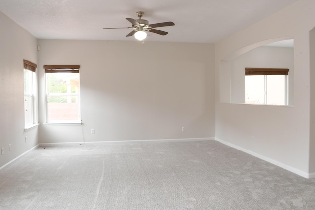 spare room featuring a wealth of natural light, light colored carpet, and ceiling fan