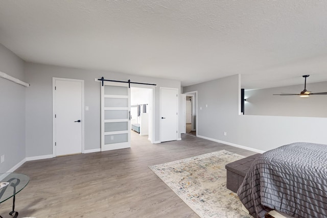 13428 Panorama Loop NE, Albuquerque, NM 87123 - bedroom with baseboards, a barn door, wood finished floors, and a textured ceiling
