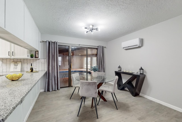 dining area with light hardwood / wood-style floors, a textured ceiling, and an AC wall unit