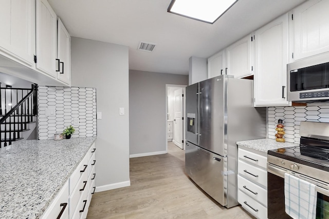 kitchen with white cabinetry, tasteful backsplash, stainless steel appliances, light stone countertops, and light hardwood / wood-style floors