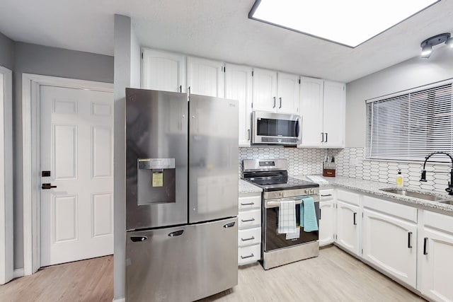 13428 Panorama Loop NE, Albuquerque, NM 87123 - kitchen featuring stainless steel appliances, a sink, light wood-style floors, and white cabinetry