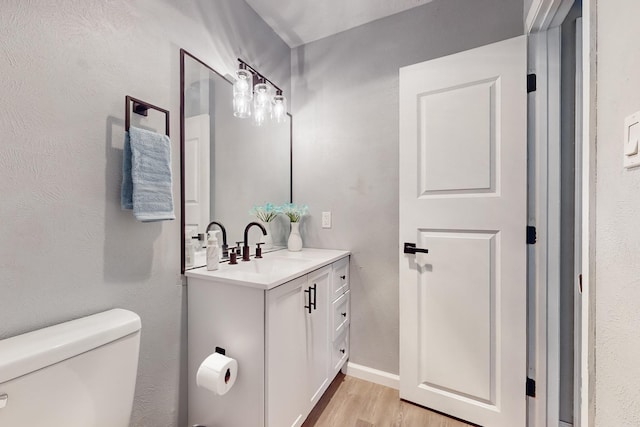 bathroom featuring wood-type flooring, toilet, and vanity