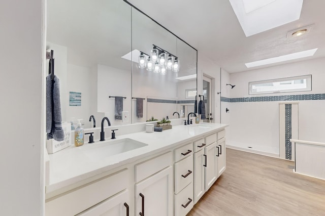 bathroom featuring hardwood / wood-style flooring, vanity, a shower, and a skylight