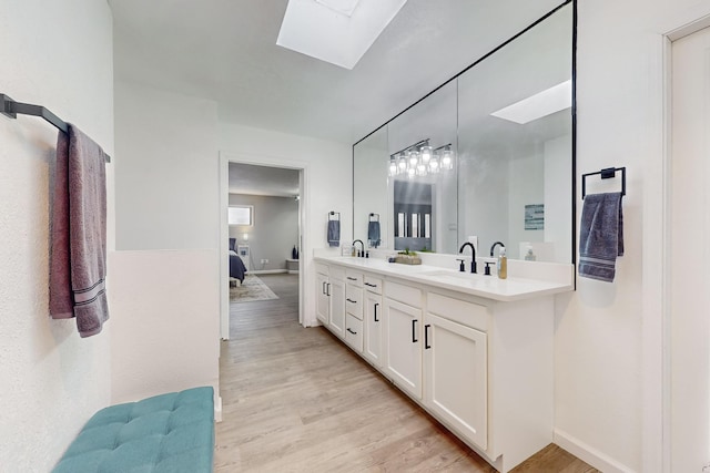 bathroom featuring vanity, hardwood / wood-style flooring, and a skylight