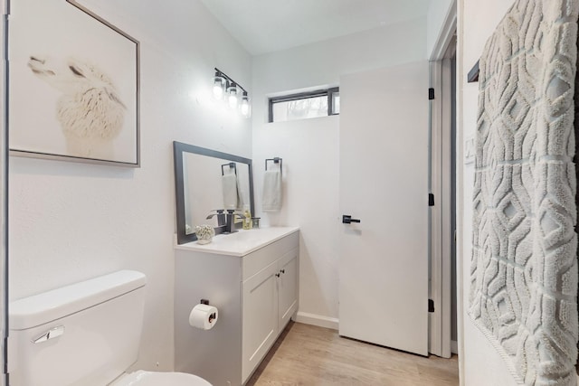 bathroom with vanity, toilet, and hardwood / wood-style floors