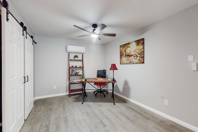 home office with light hardwood / wood-style floors, a wall unit AC, a barn door, and ceiling fan