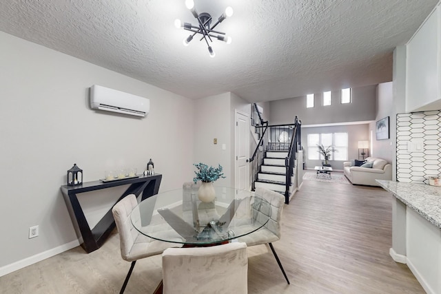 13428 Panorama Loop NE, Albuquerque, NM 87123 - dining room featuring a wall mounted air conditioner, stairs, light wood-style floors, a textured ceiling, and baseboards