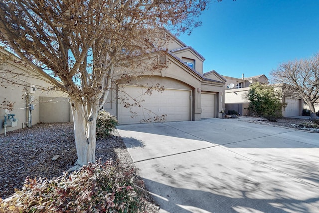 view of front of house with an attached garage, a tile roof, concrete driveway, and stucco siding