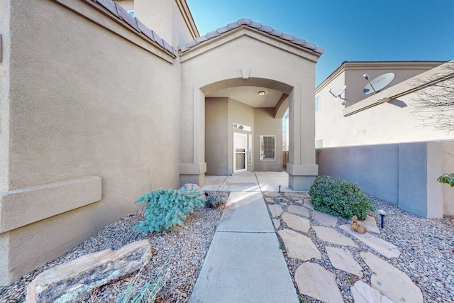 view of exterior entry with a patio area and stucco siding