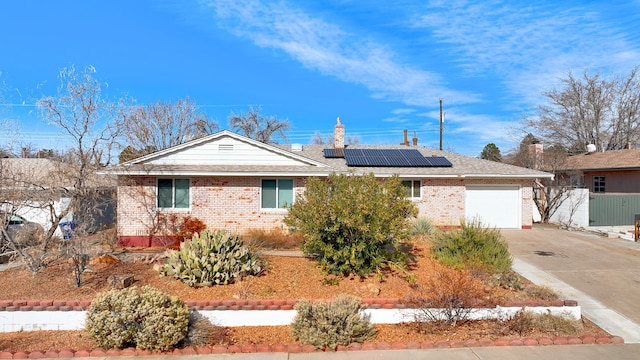 single story home with a garage and solar panels