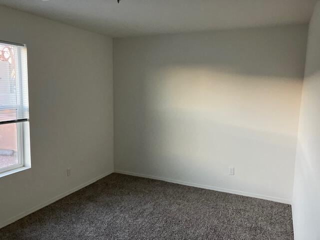 spare room with dark colored carpet