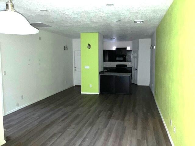 unfurnished living room with dark wood-type flooring and a textured ceiling