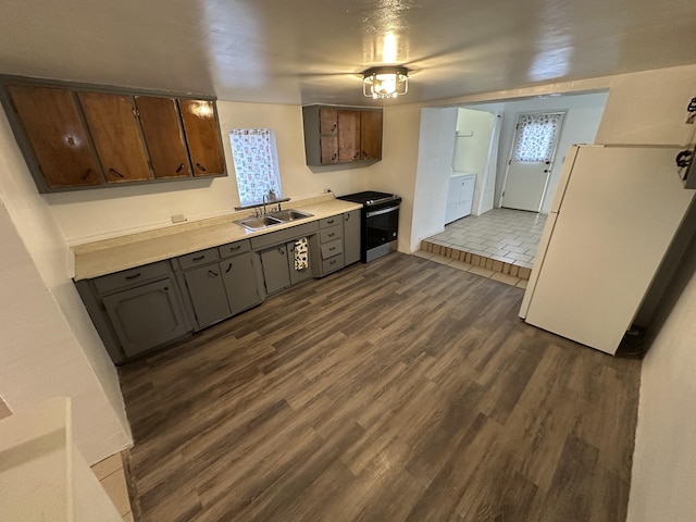 kitchen featuring dark wood-type flooring, sink, dark brown cabinets, stainless steel range with gas cooktop, and washing machine and dryer