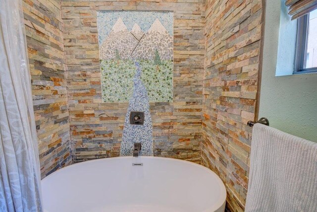 full bathroom featuring a soaking tub and a textured wall