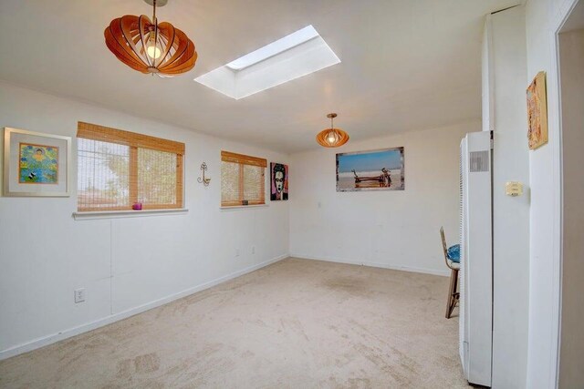 carpeted spare room with a skylight and baseboards