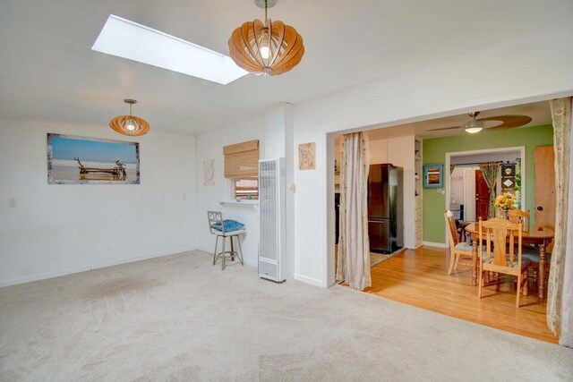 living room featuring carpet flooring, ceiling fan, and a skylight