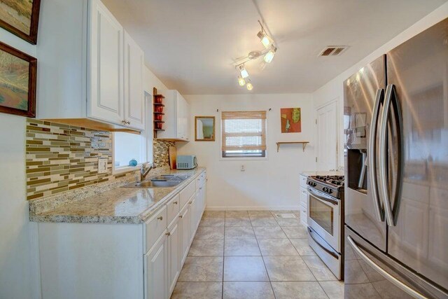 kitchen with visible vents, a sink, tasteful backsplash, white cabinetry, and stainless steel appliances