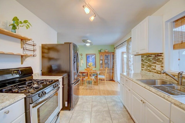 kitchen with open shelves, a sink, stainless steel appliances, white cabinets, and backsplash