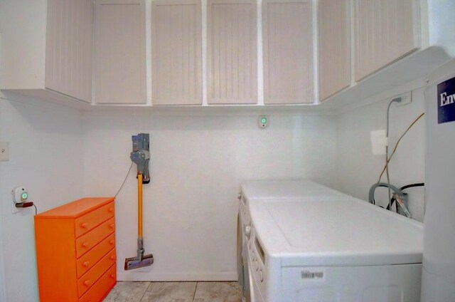 laundry room featuring light tile patterned floors, cabinet space, and washing machine and clothes dryer