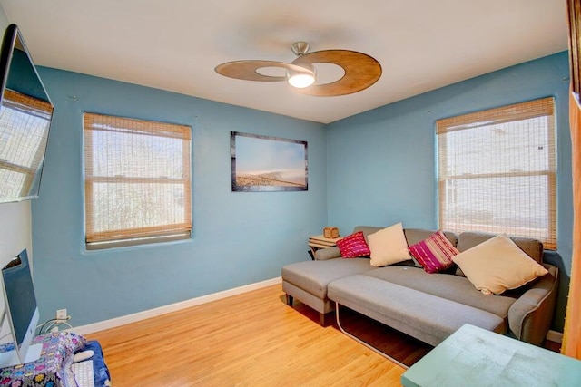 living room featuring plenty of natural light, ceiling fan, baseboards, and wood finished floors