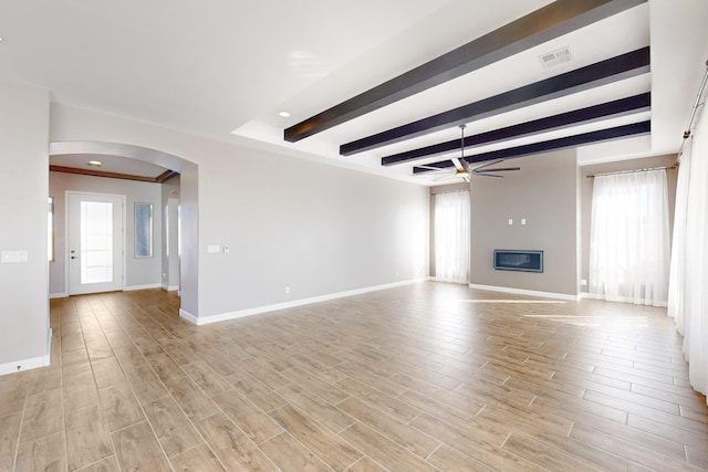 unfurnished living room featuring a healthy amount of sunlight, beamed ceiling, ceiling fan, and light wood-type flooring