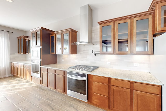 kitchen with appliances with stainless steel finishes, light stone countertops, extractor fan, and backsplash