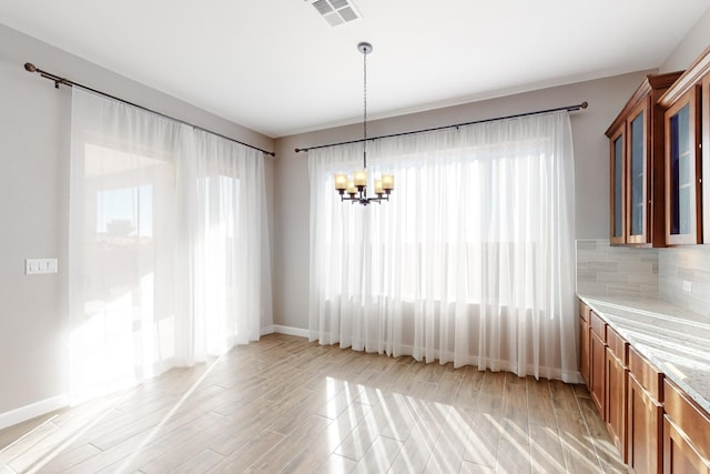 unfurnished dining area with a chandelier and light hardwood / wood-style flooring