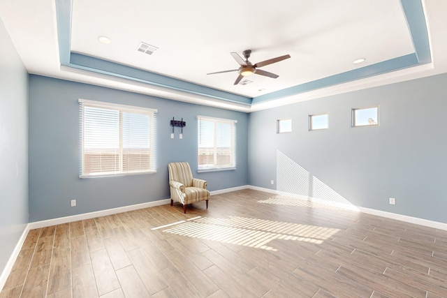 unfurnished room featuring a tray ceiling and light hardwood / wood-style floors