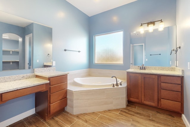 bathroom featuring vanity and tiled tub