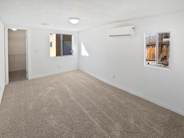 carpeted empty room with an AC wall unit and a textured ceiling