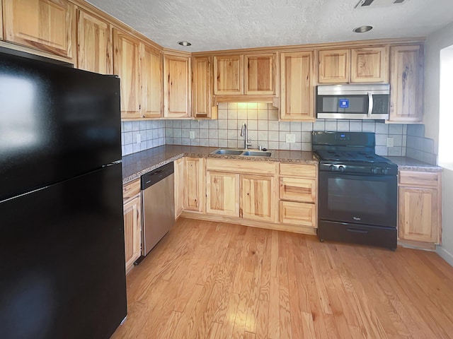 kitchen with light brown cabinetry, sink, light hardwood / wood-style flooring, and black appliances