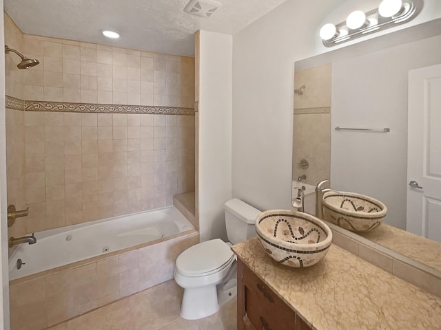 full bathroom featuring tiled shower / bath combo, vanity, a textured ceiling, tile patterned floors, and toilet