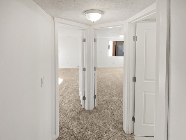 hall featuring a textured ceiling and carpet