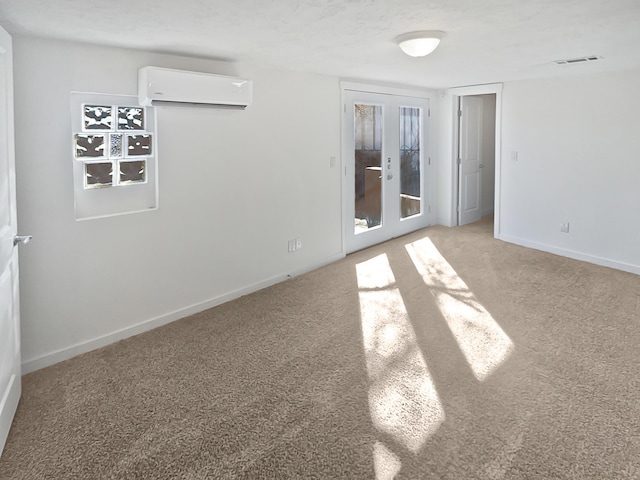 carpeted empty room featuring a wall unit AC and french doors