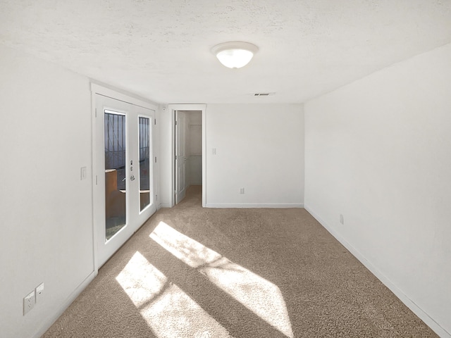 carpeted empty room featuring french doors and a textured ceiling